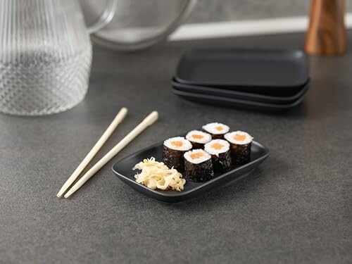 Sushirolletjes met gember en eetstokjes op tafel.