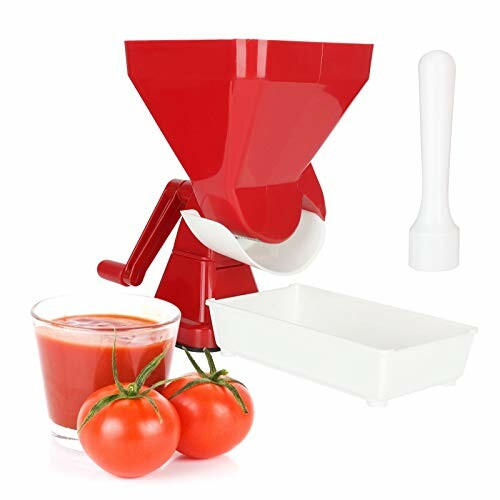 Rode handmatige sapmachine met tomaten en glas sap